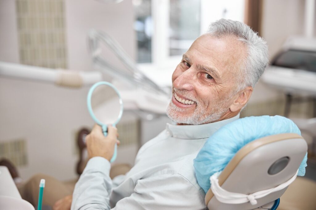 elderly man smiling while sitting dental chair looking happy with his treatment 317809 3017 elderly man smiling while sitting dental chair looking happy with his treatment 317809 3017