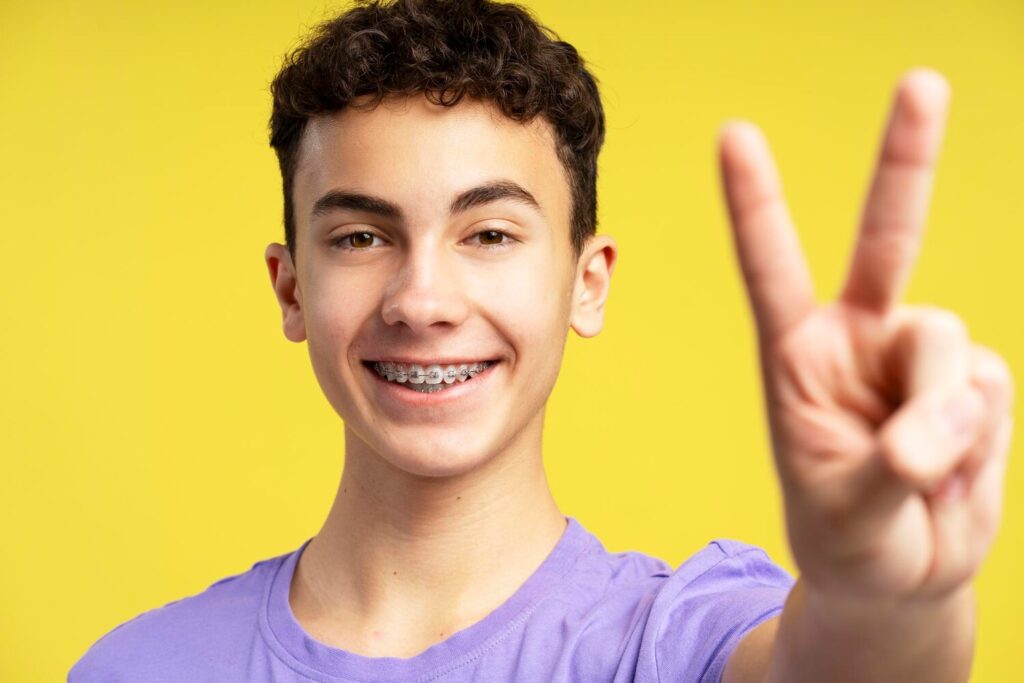 portrait positive handsome boy with braces gesturing showing peace sign with fingers 695242 7607 portrait positive handsome boy with braces gesturing showing peace sign with fingers 695242 7607