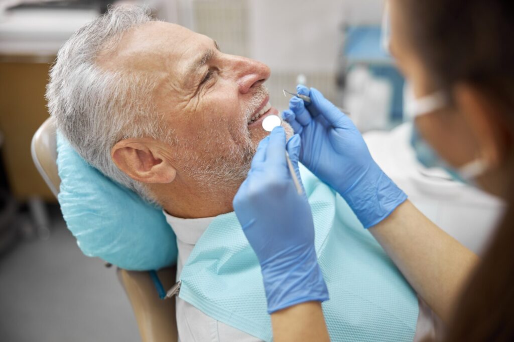 professional dental specialsit holding mouth mirror dental pick while examining elderly man 317809 3034 professional dental specialsit holding mouth mirror dental pick while examining elderly man 317809 3034