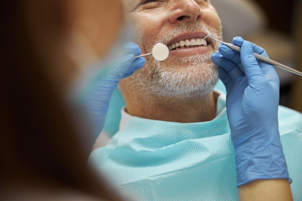 senior man smiling while doctor examining his teeth with dental tools 317809 3033 senior man smiling while doctor examining his teeth with dental tools 317809 3033